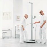 man in white t-shirt and white pants standing on black exercise equipment